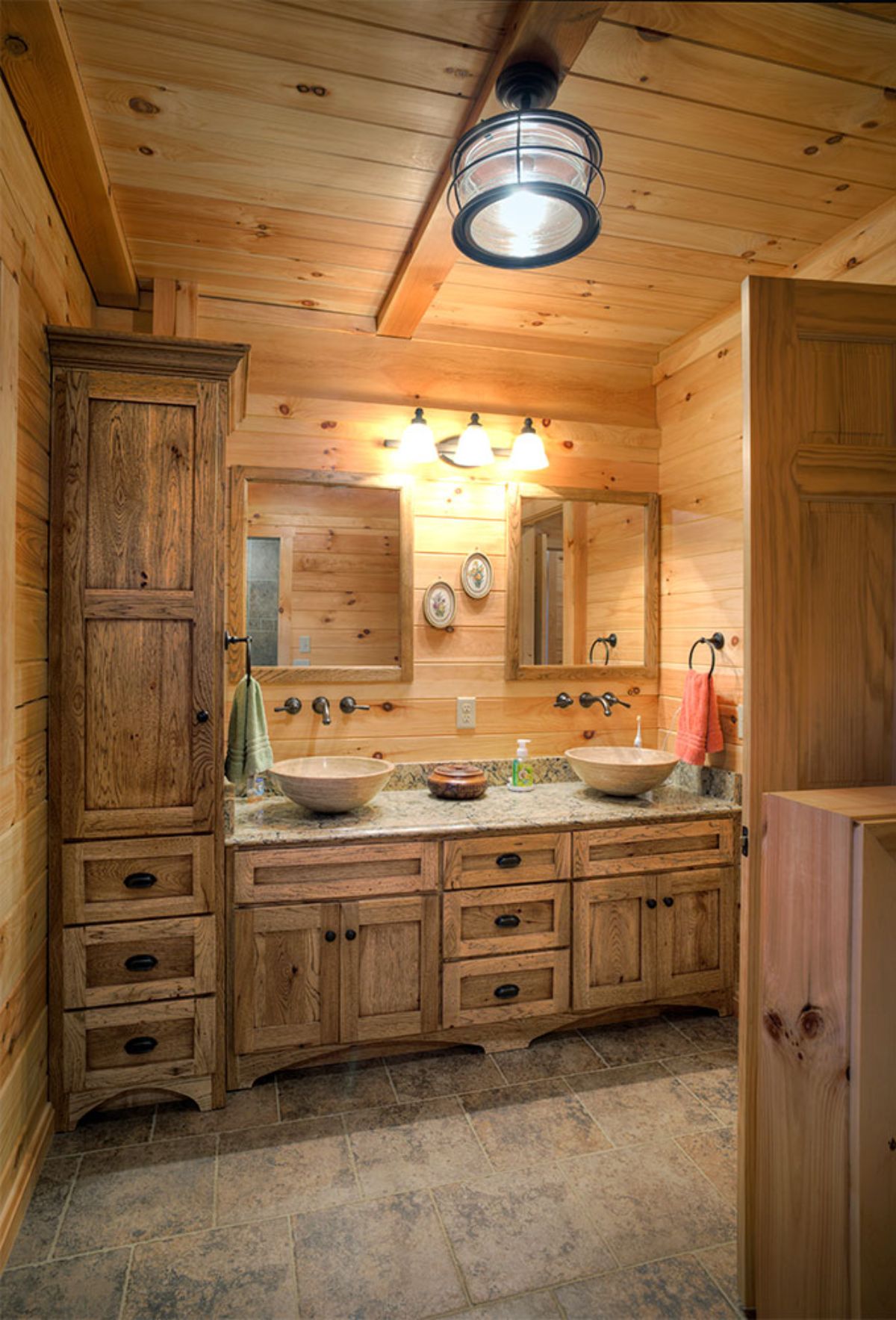 light wood stained cabinets in bathroom with bowl sinks and two mirrors