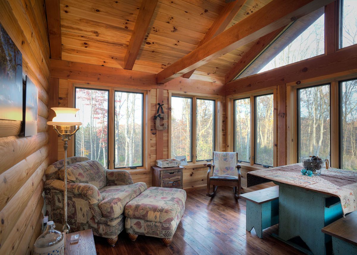 great room with windows on all sides and light floral chairs on right side