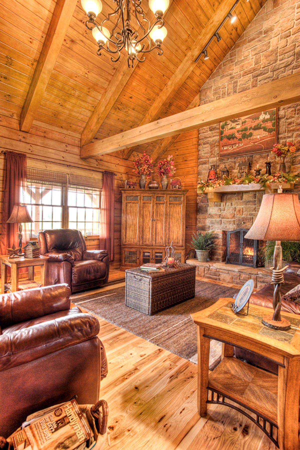 log cabin with brown leather sofa and recliners and stone fireplace on right wall