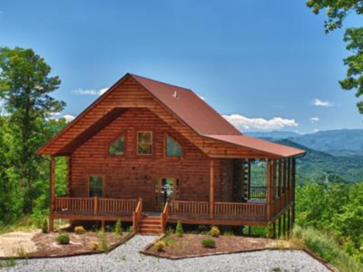Brown cabin on hill with mountain in background