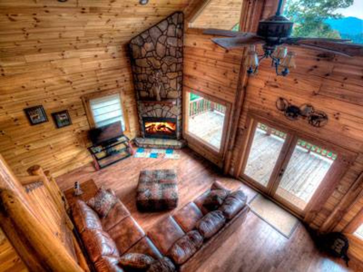 view down into cabin living room with sofas and wall of windows