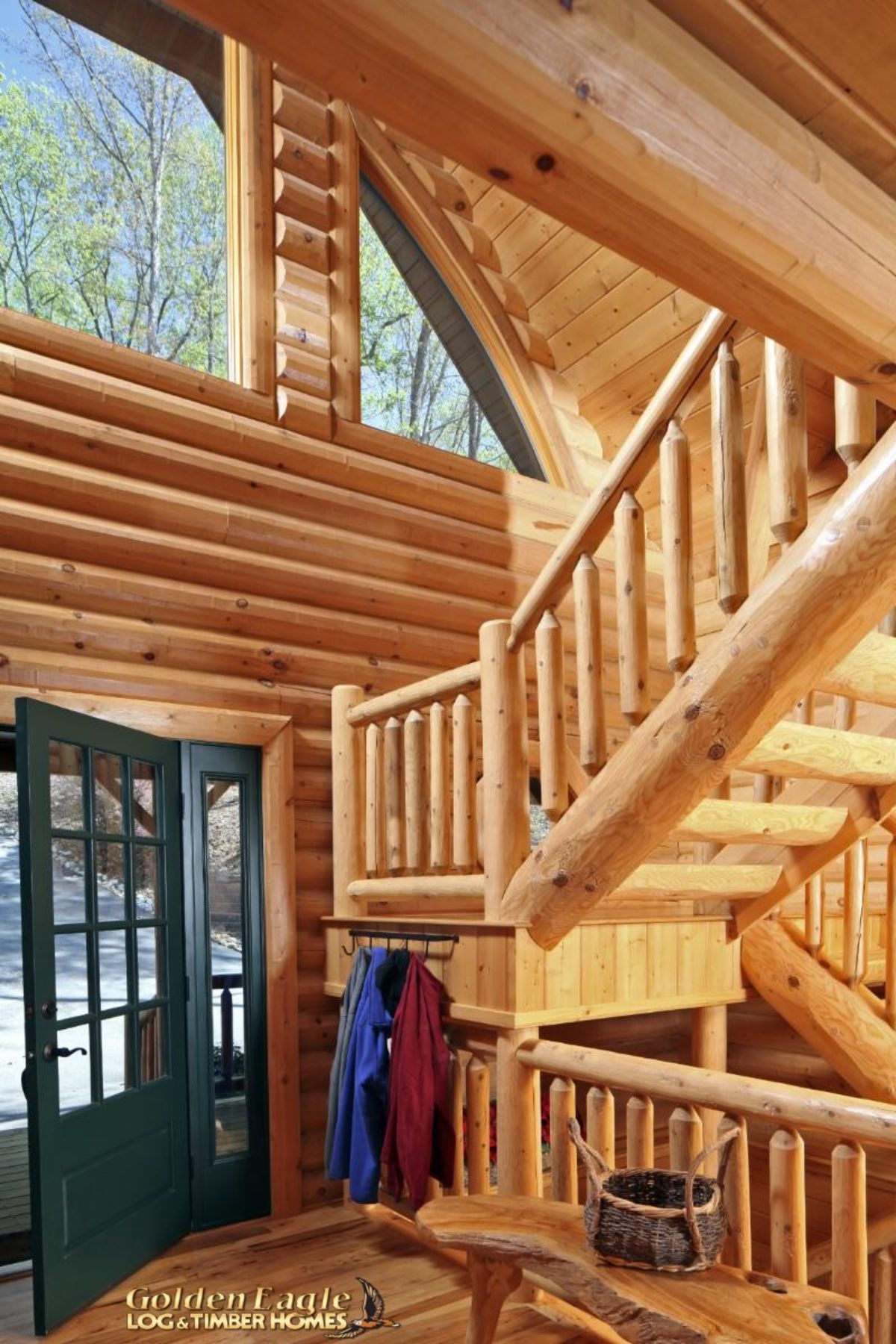 wood stair case with log railing inside log cabin with green door