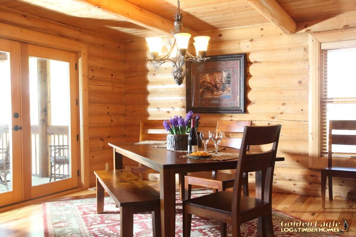 wood table in chairs next to french doors inside log cabin