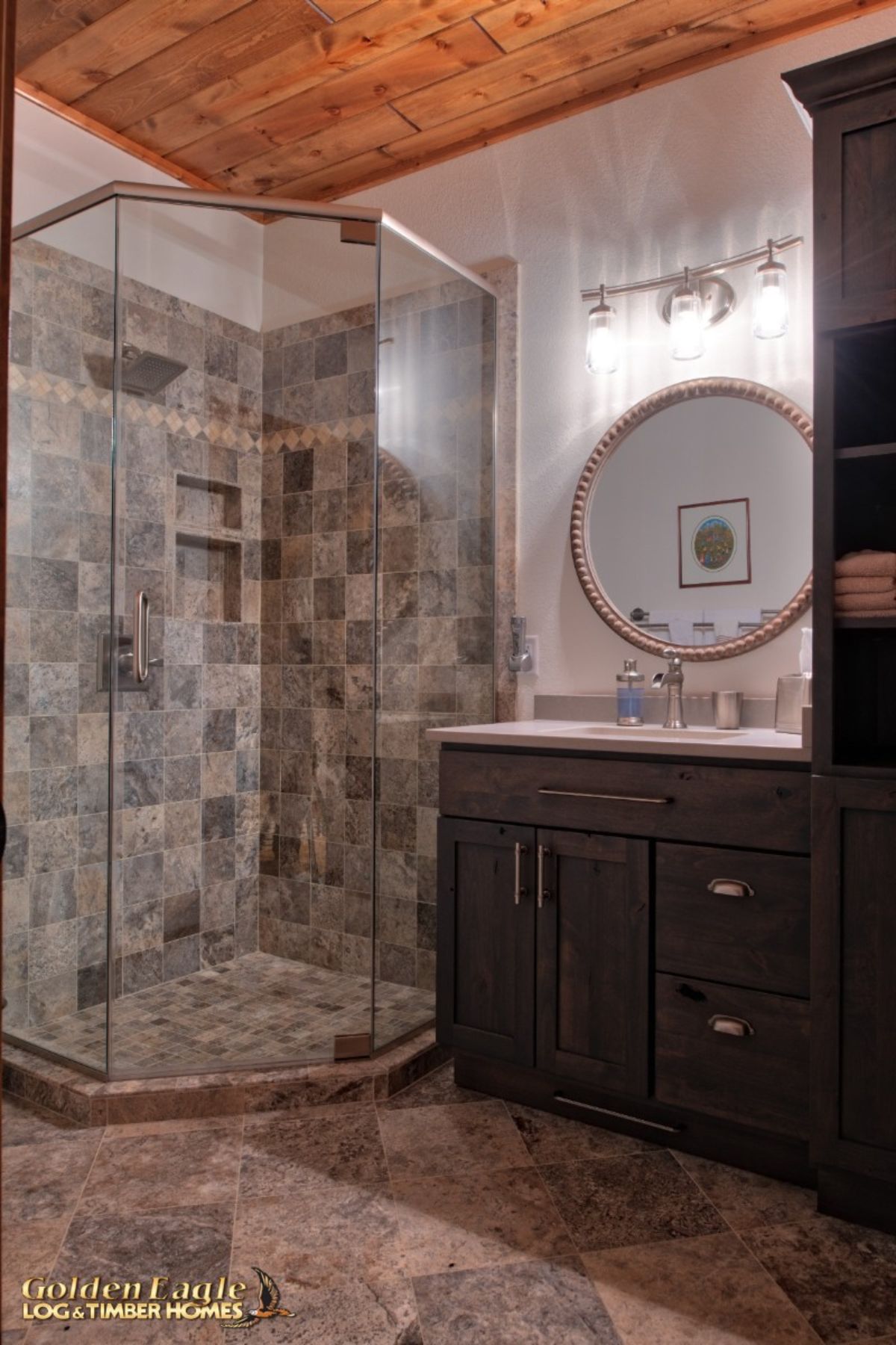 white and gray tile in glass shower next to dark wood vanity with round mirror on white wall above