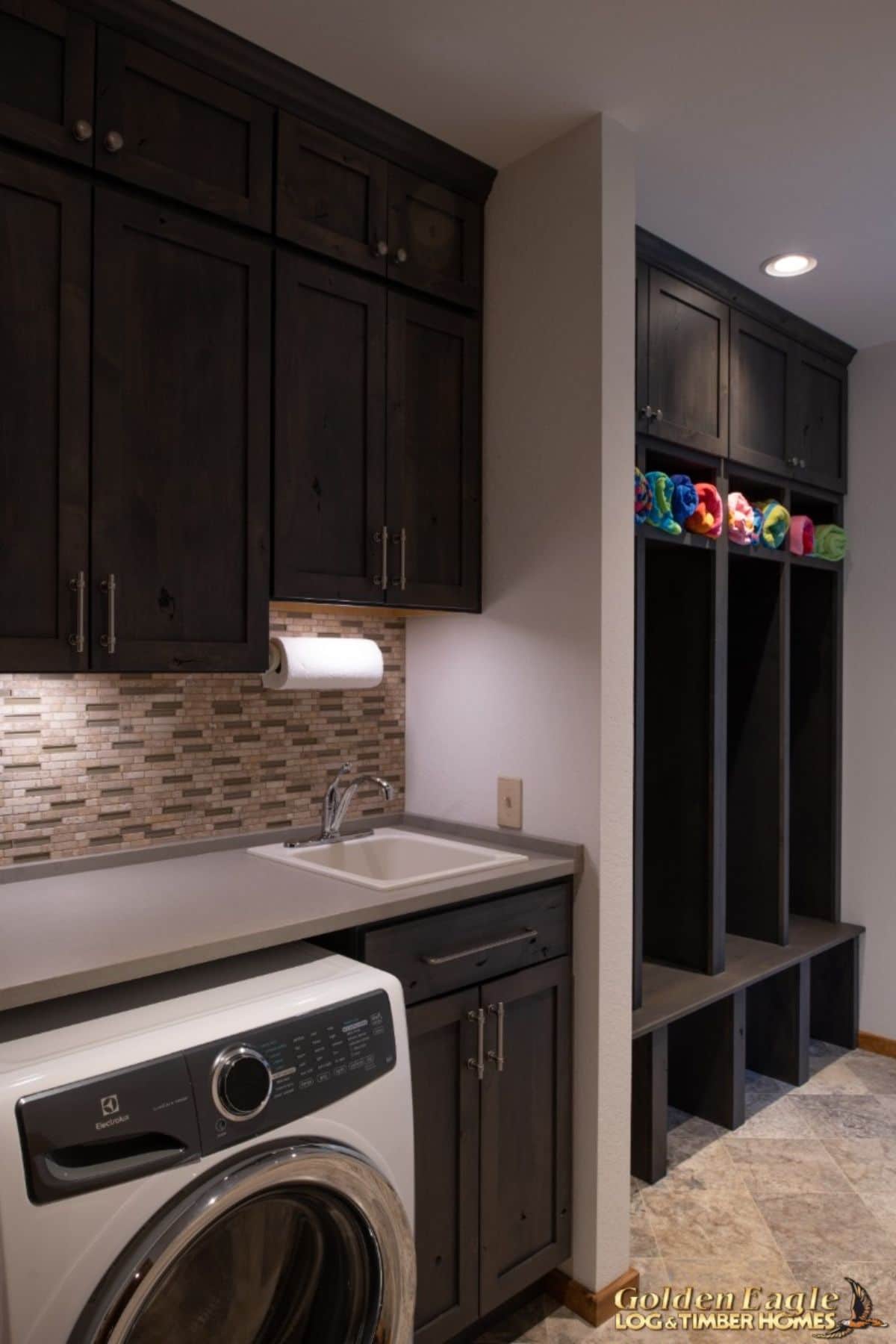 black cabinets in laundry space with gray backsplash and countertop