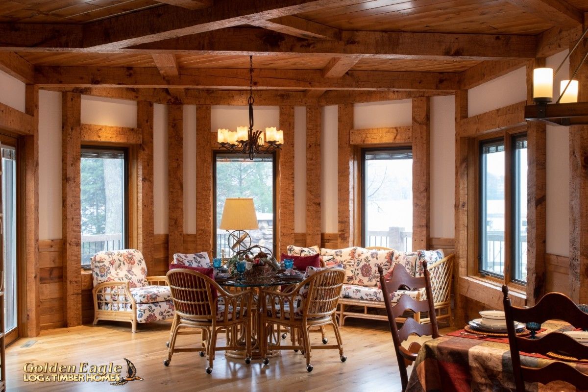 wall of glass windows behind table in dining nook of log cabin