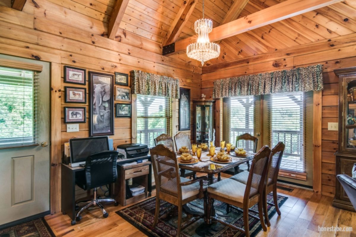 dining table next to light green wood door in log cabin