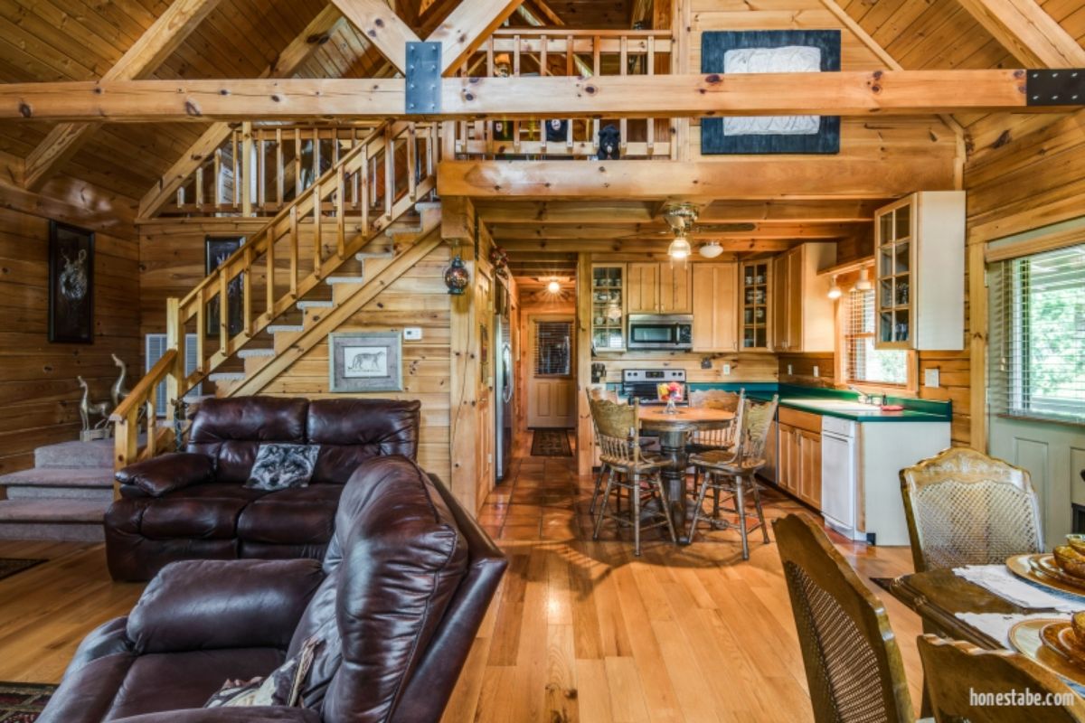main living space in log cabin with table to right and black sofa to left