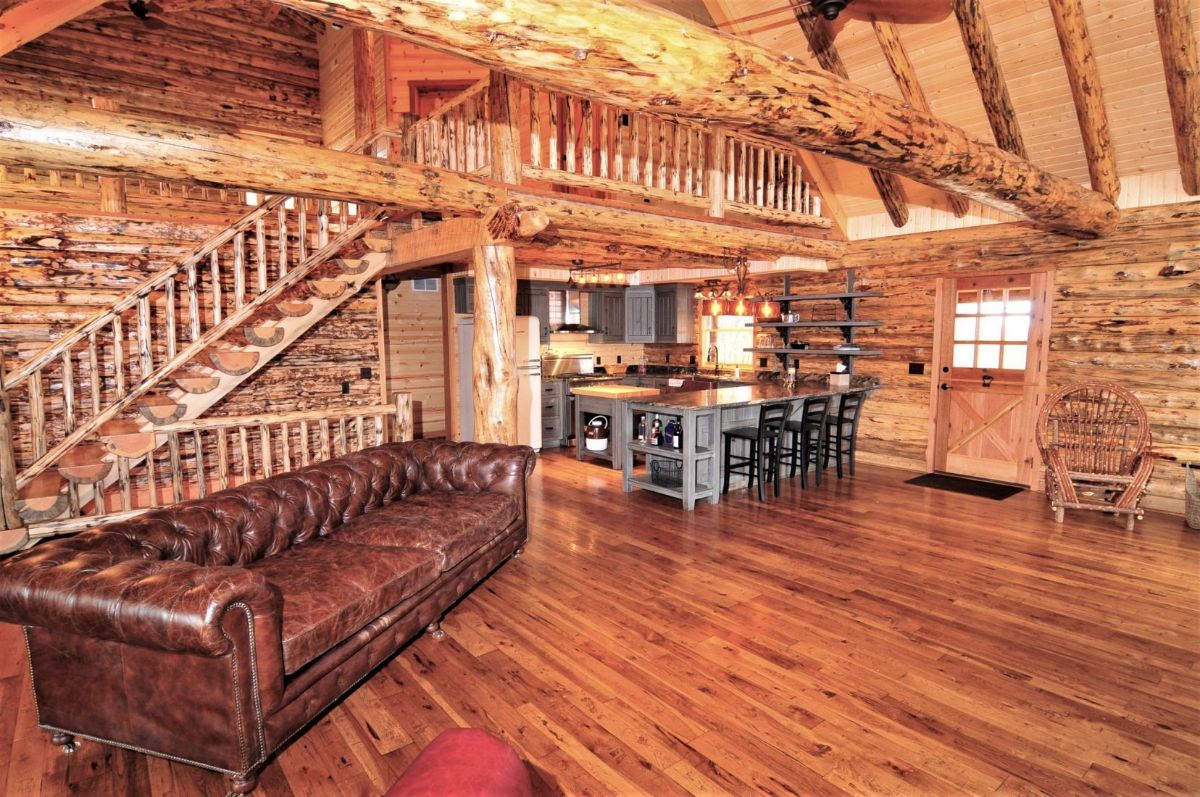 brown leather sofa against left wall of log cabin