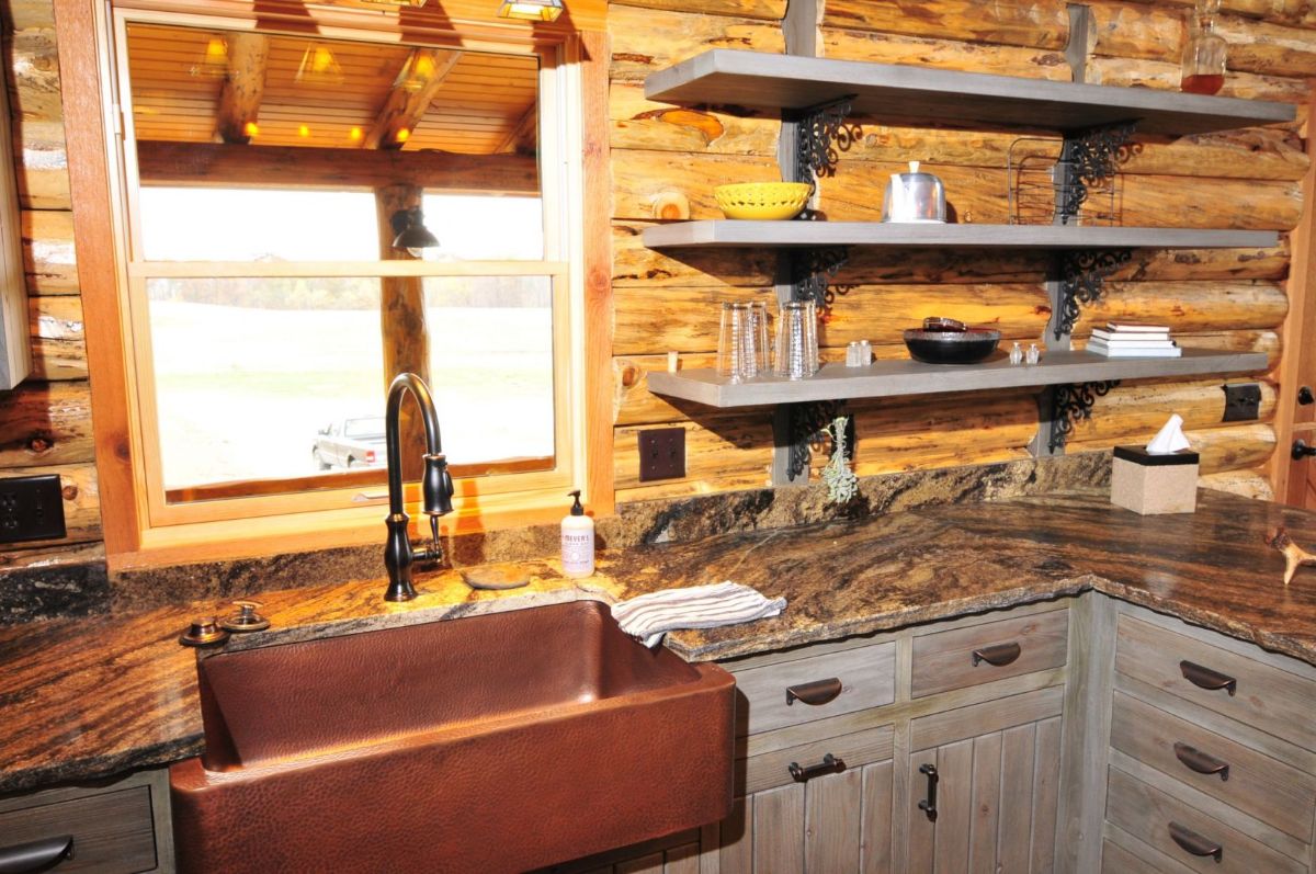 copper farmhouse sink in gray cabinets with granite countertops