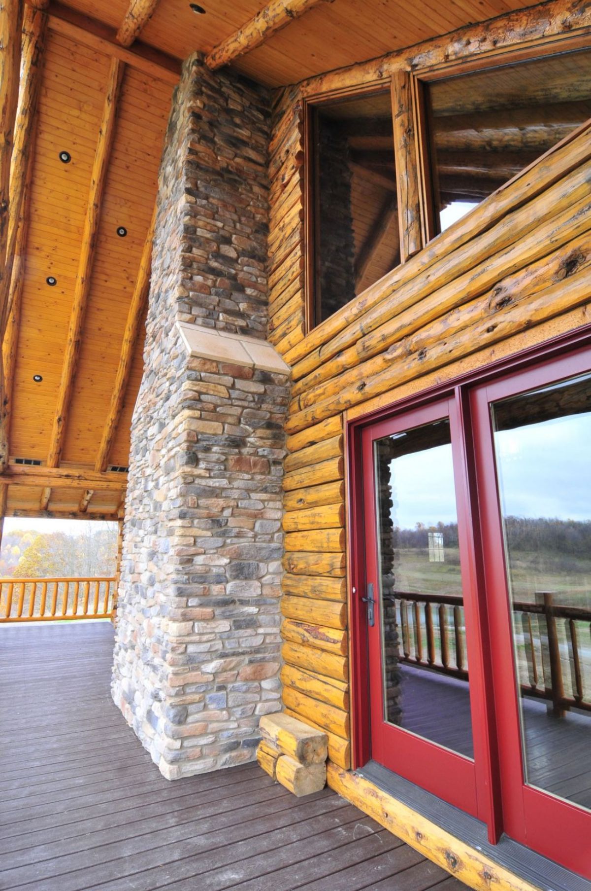stone chimney on back of log cabin with red trim