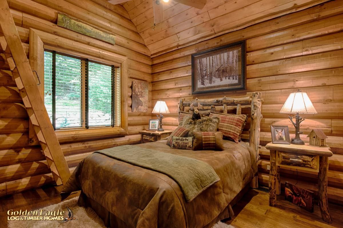 bed against log cabin wall with ladder against left wall