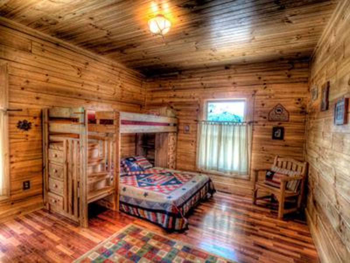 bunk beds against log cabin wall with chair in corner
