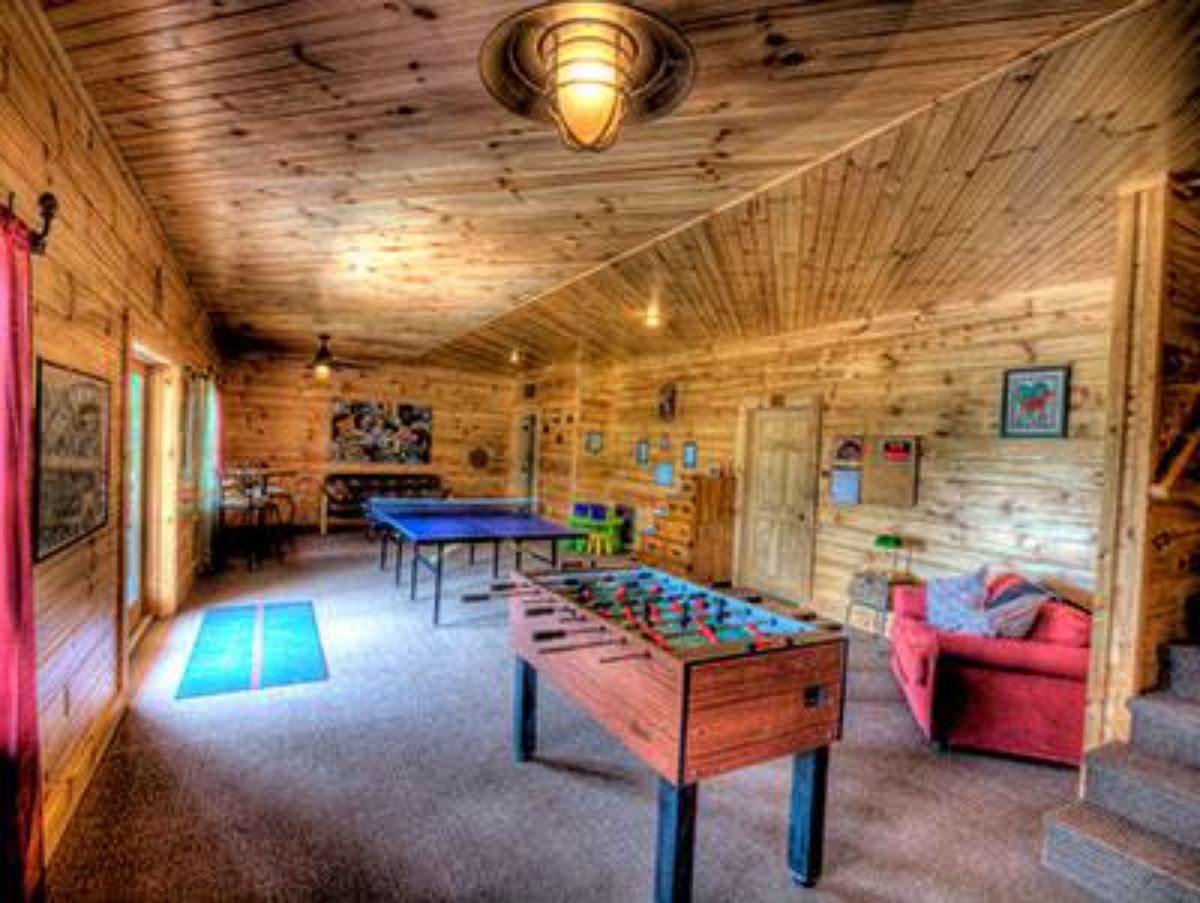 foosball table in log cabin game room with red sofa in background