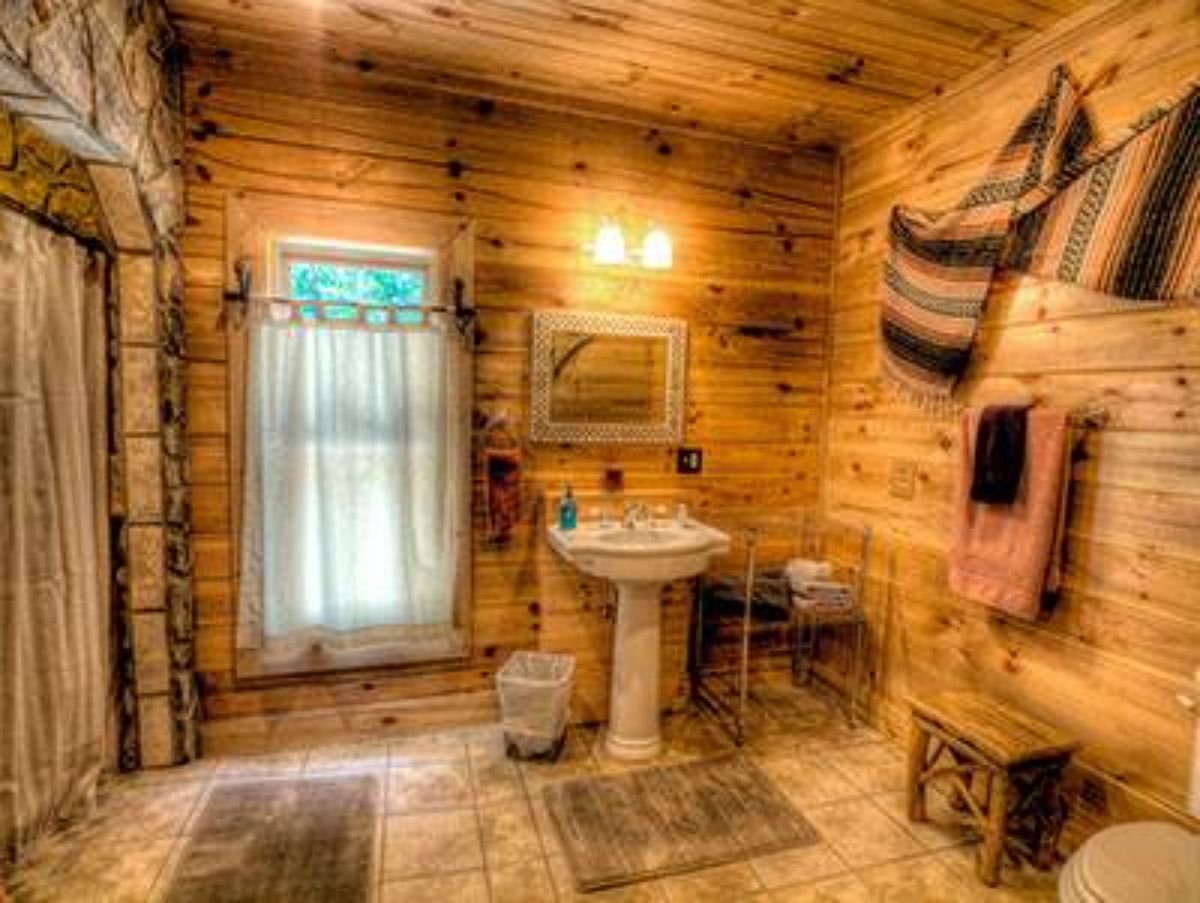 white pedastal sink against back wall of log cabin