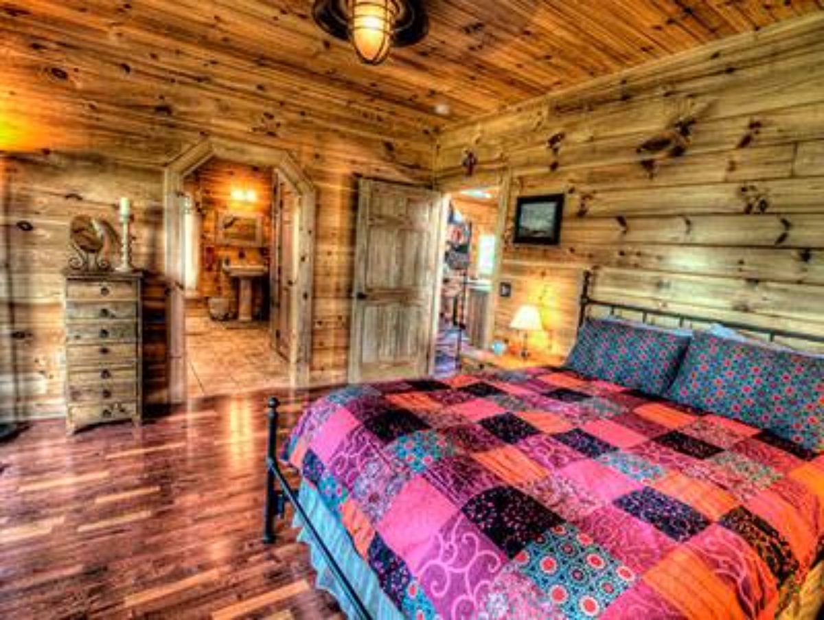 red and black quilt on black bedframe in log cabin bedroom with arch doorways