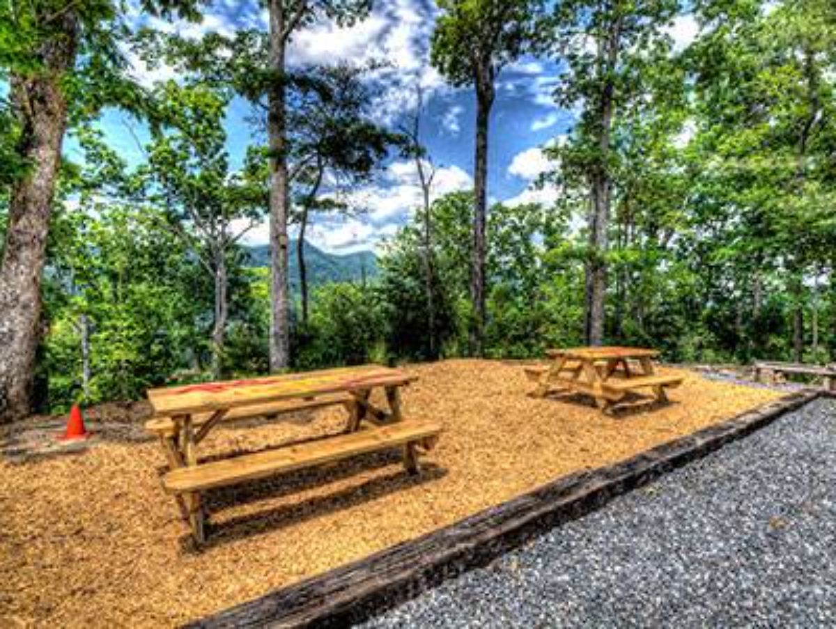 two wood picnic tables next to gravel driveway
