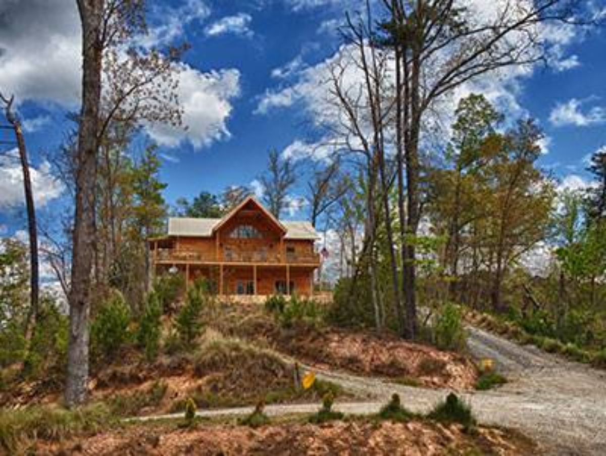 driveway and rock path up to log cabin against cloudy sky