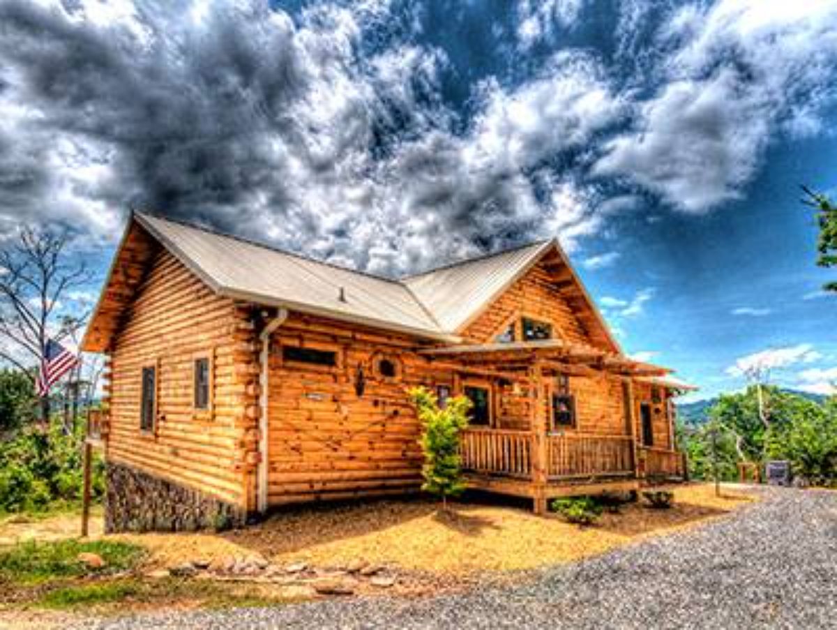 log cabin with light wood and light roof against colorful cloudy sky