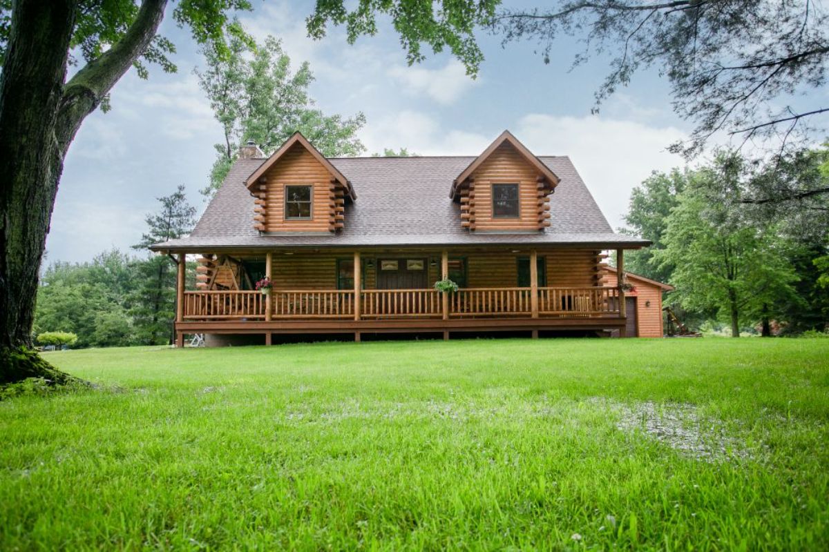 log cabin with light wood stain and two dormer windows on front