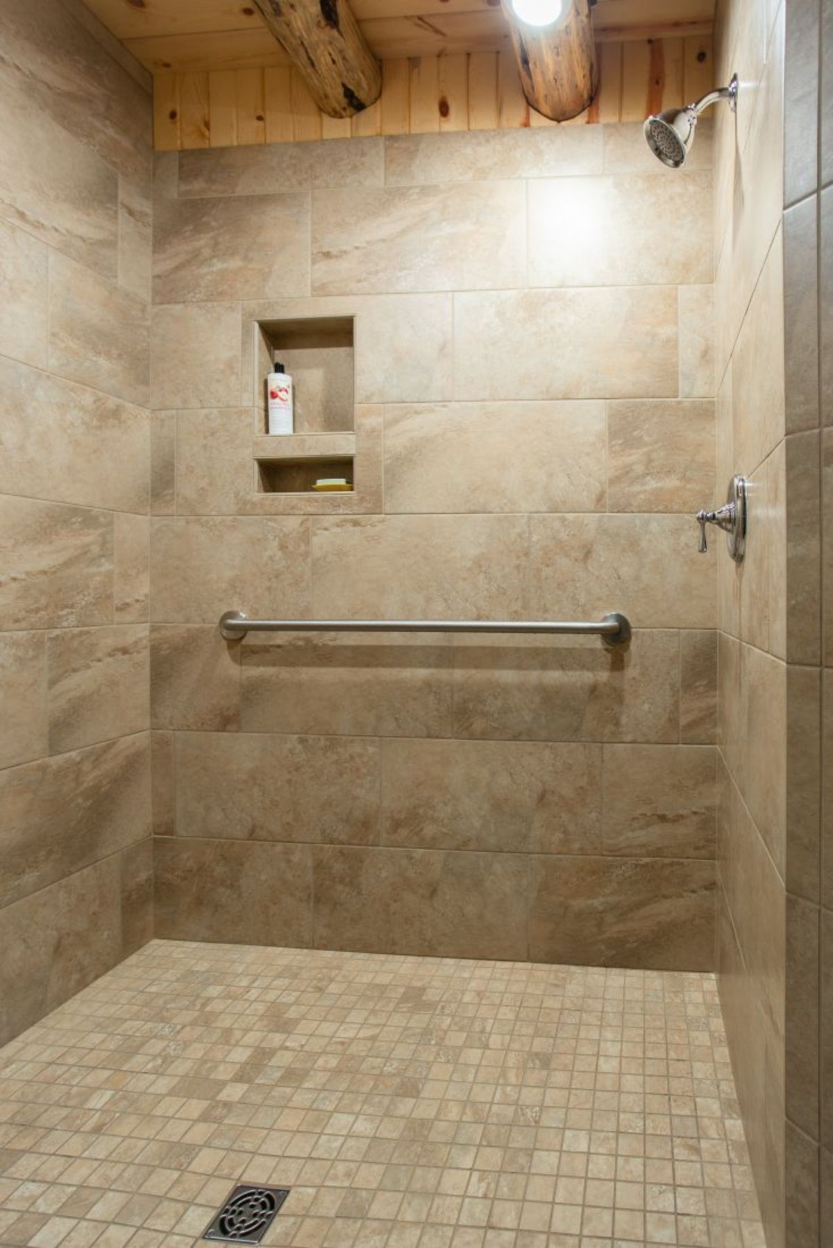 cream tile shower with built in shampoo cubby and metal bar below on wall