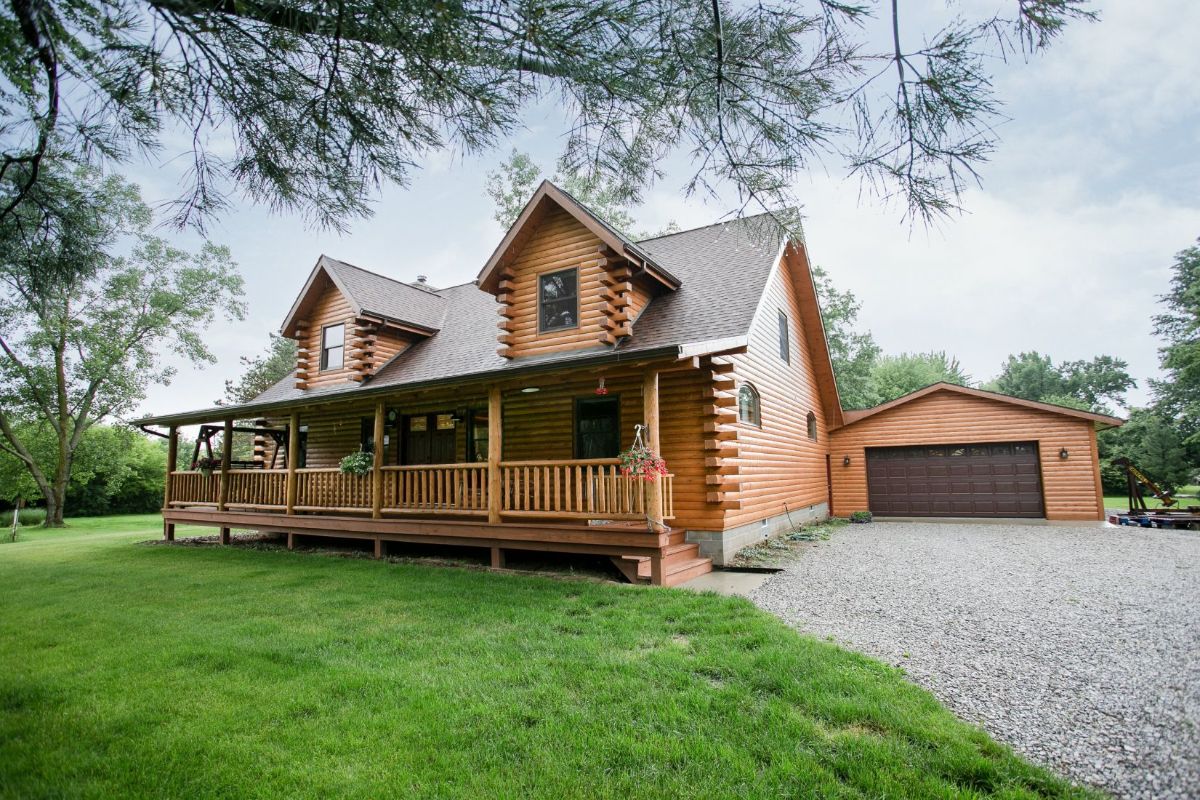 drive up to log cabin with attached garage with brown door