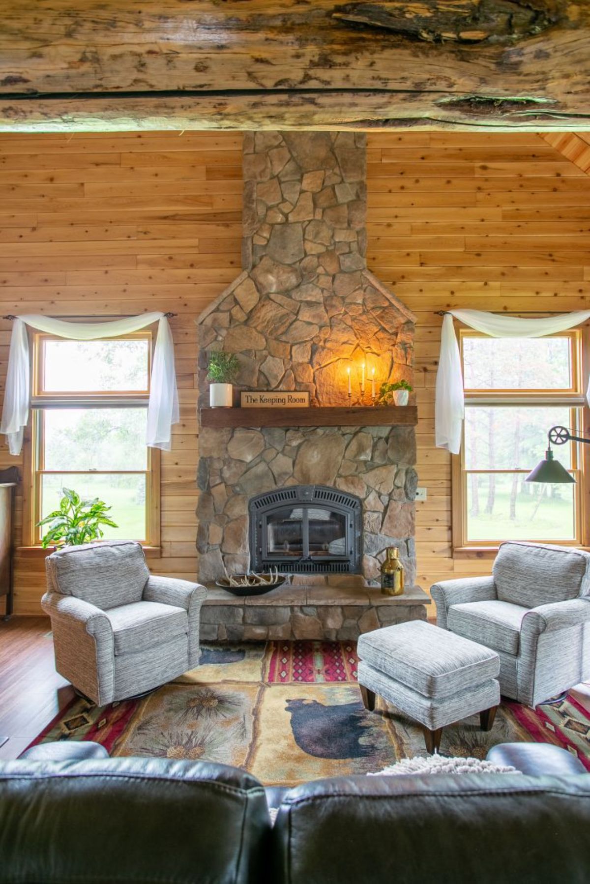 stone fireplace against log cabin wall with windows on both sides