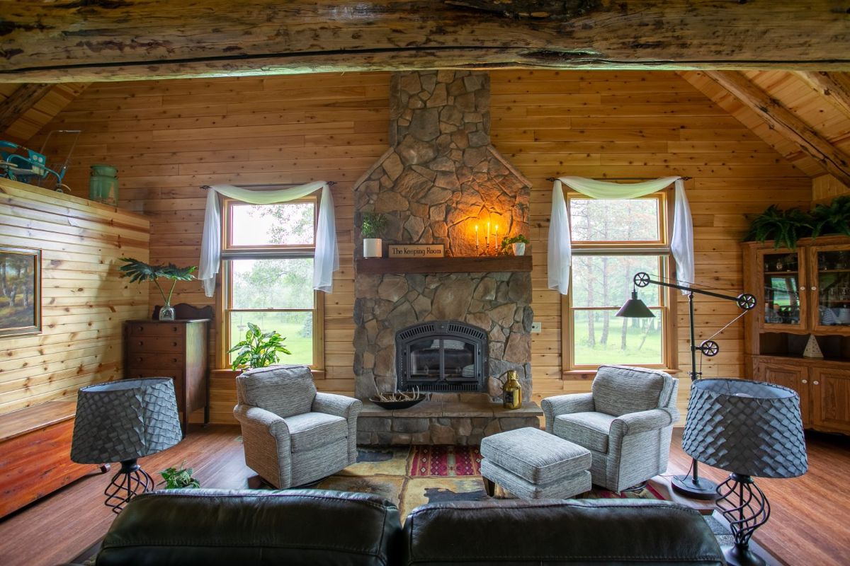 sofa and gray chairs in front of stone fireplace in log cabin