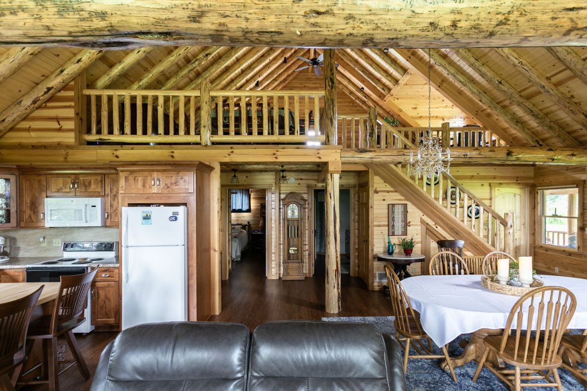 view over top of leather sofa to loft above kitchen in log cabin