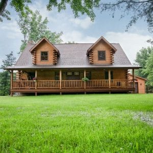 log cabin with light wood stain and two dormer windows on front