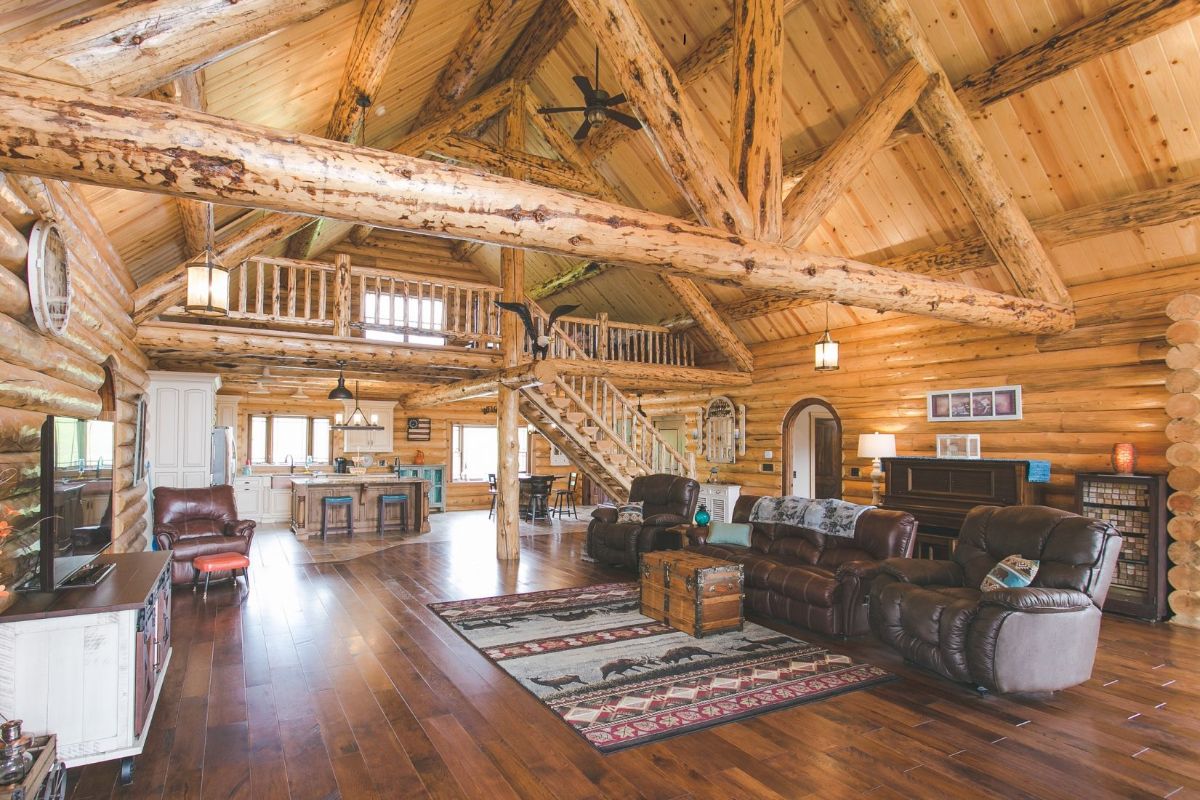 view from living area to back of log cabin showing kitchen below loft