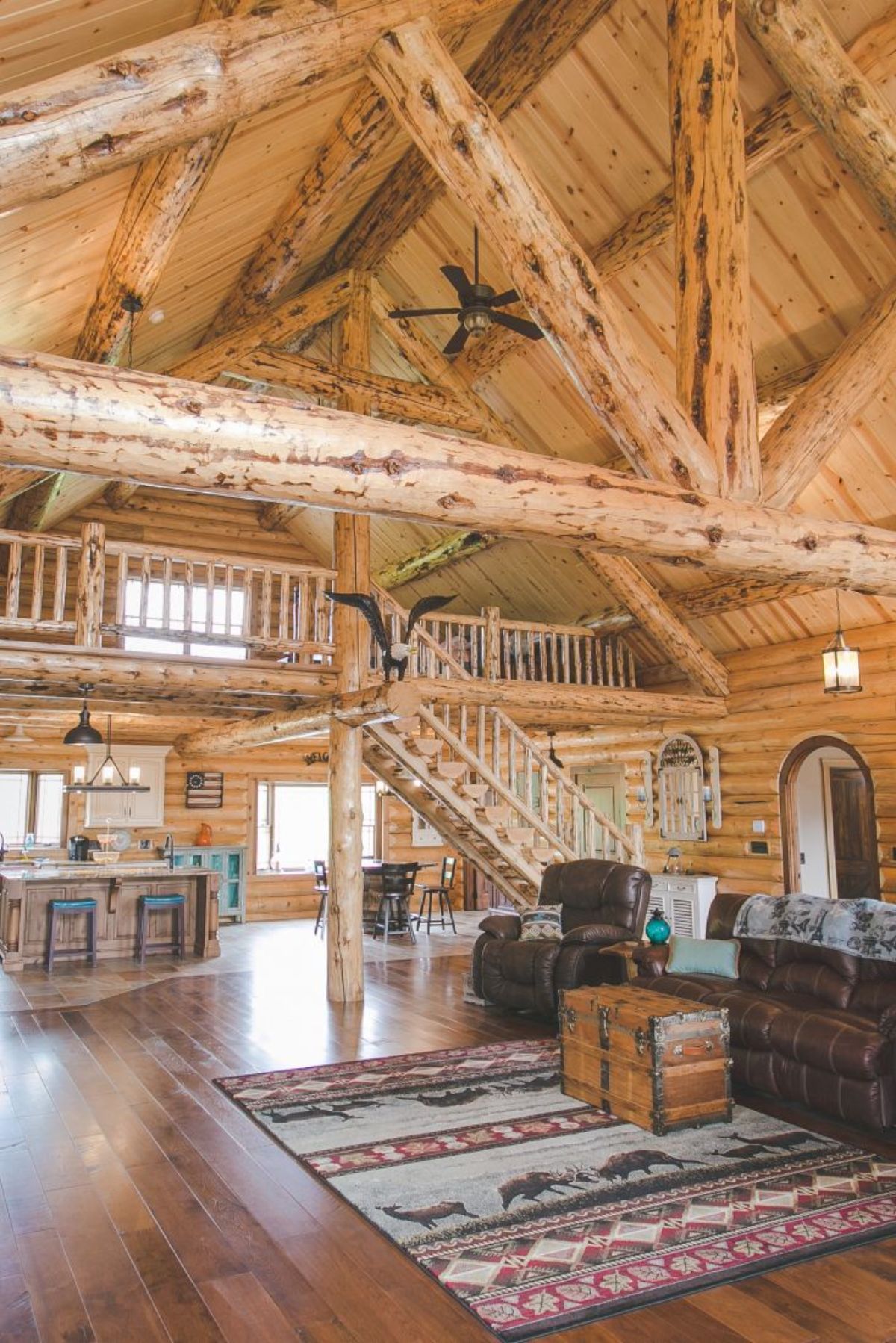 stairs to loft behind leather recliner with kitchen beneath loft