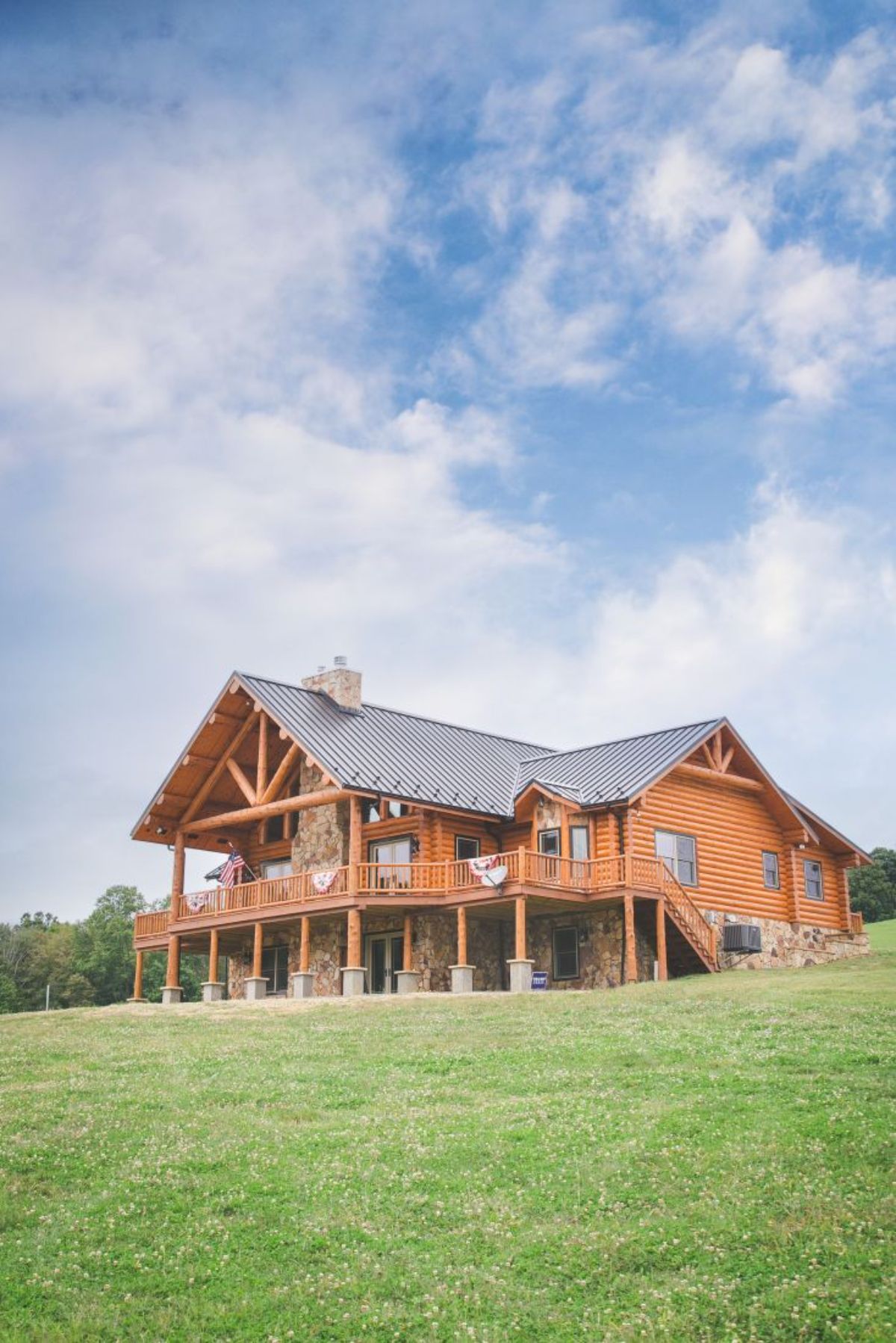 cloudy sky behind log cabin on green hill