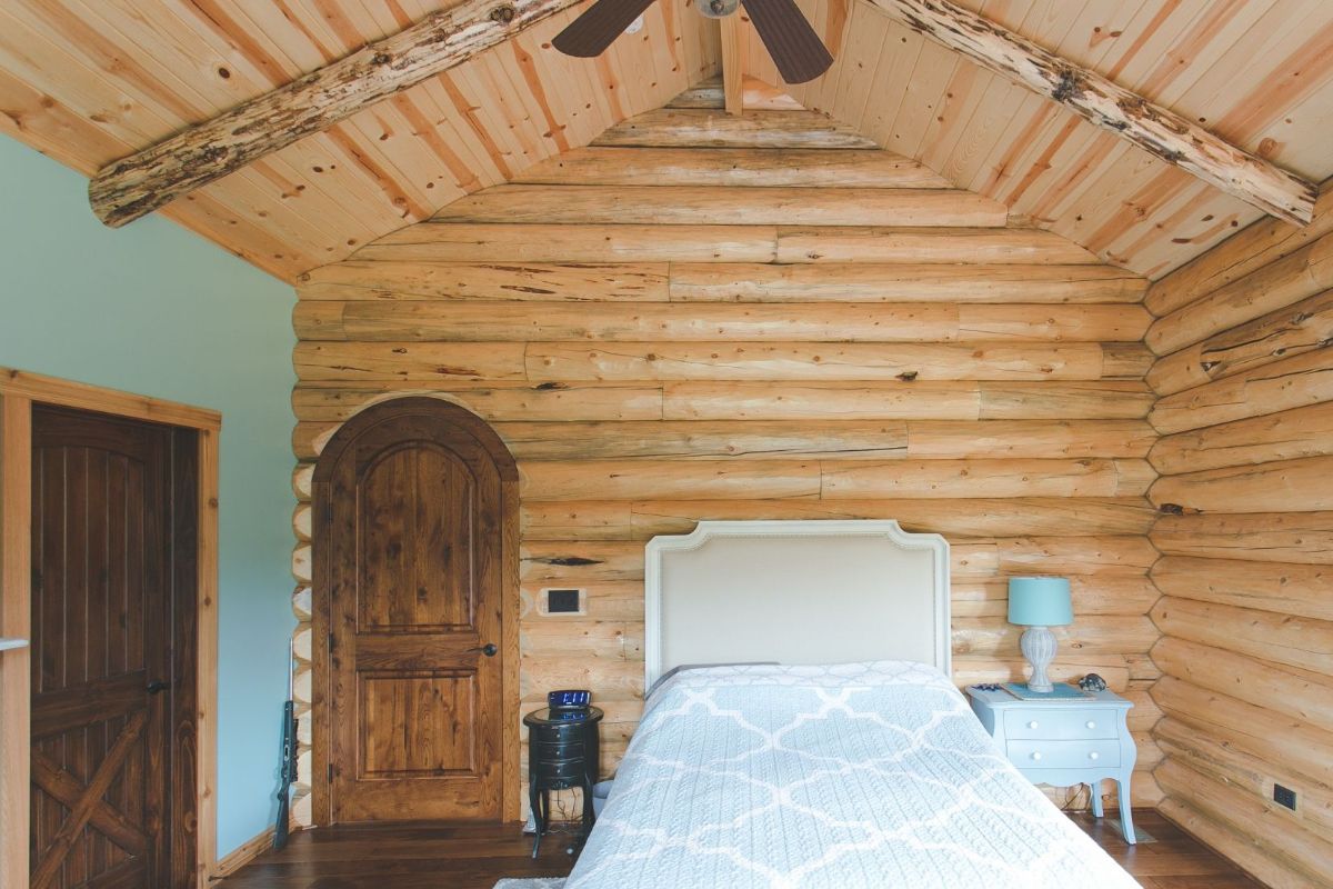 white headboard against log wall with blue wall on left