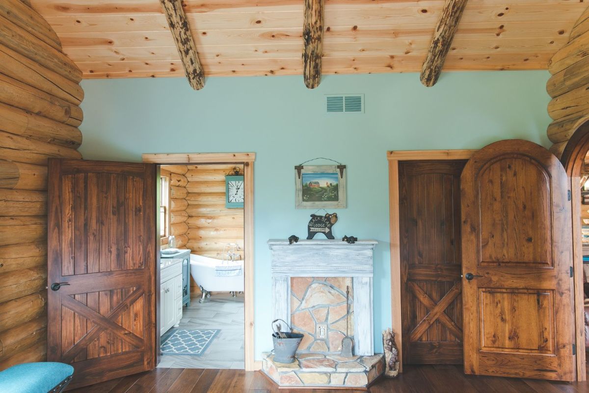 blue wall in log cabin bedroom with dark wood wardrobe next to open bathroom door