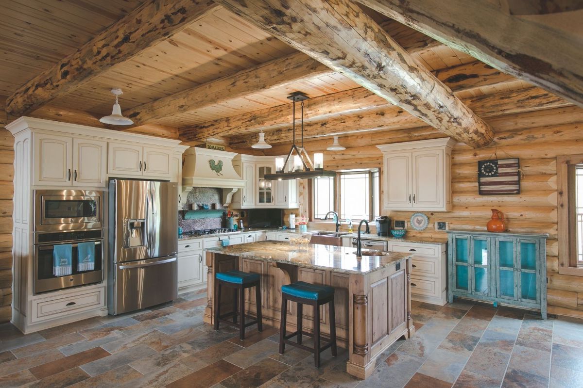 teal cabinets and accents in kitchen beneath log cabin ceiling