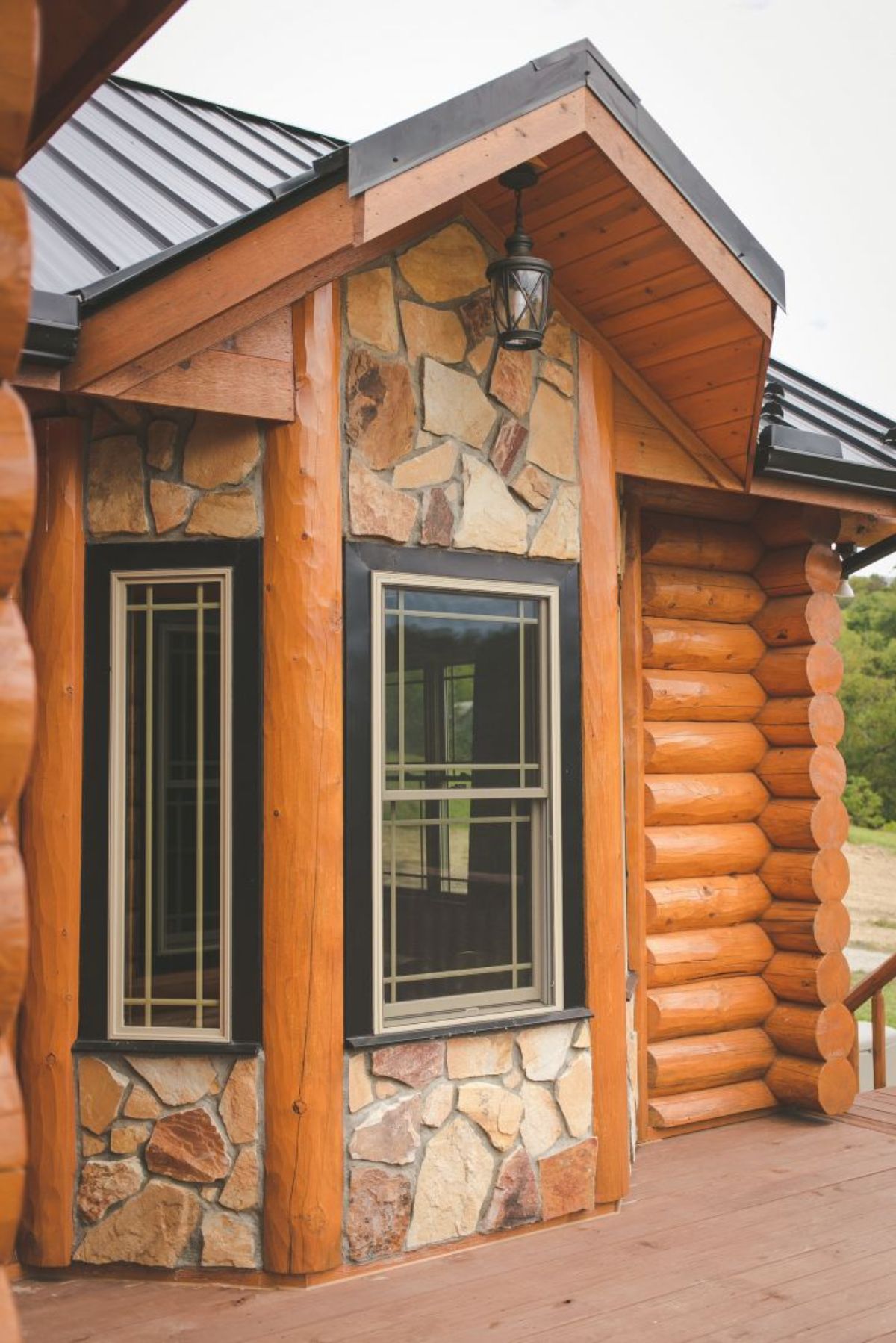 stone and log outcropping on log cabin with black trim around windows