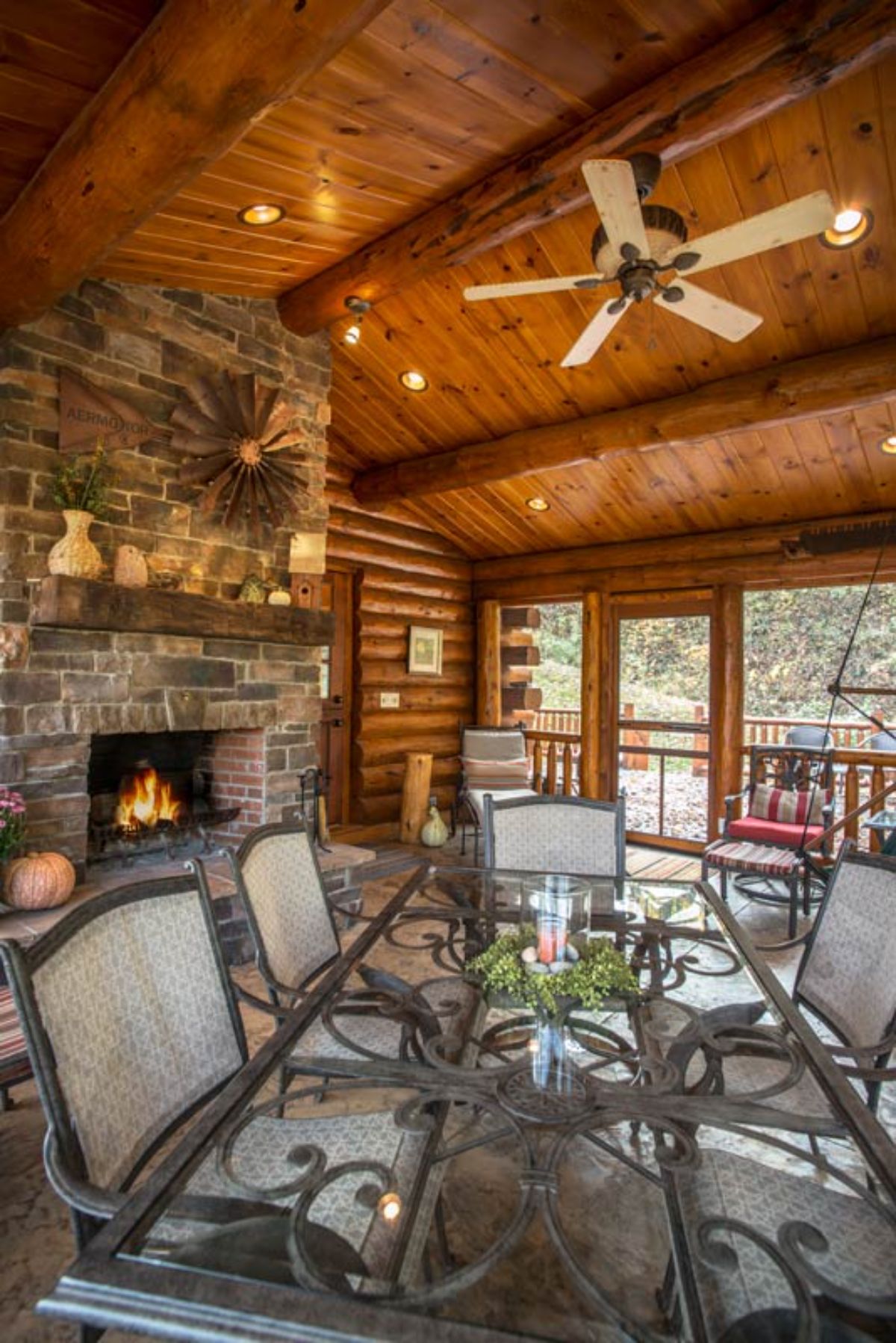 covered porch with bistro set in front of stone fireplace