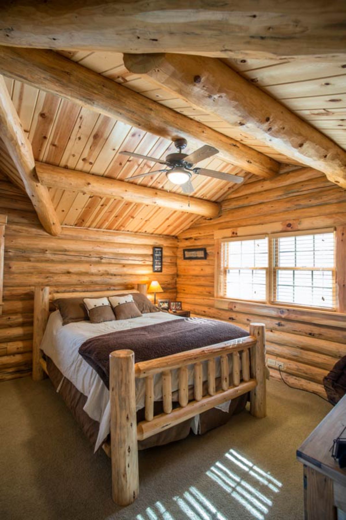 wood bed frame on bed under eaves of loft floor in log cabin