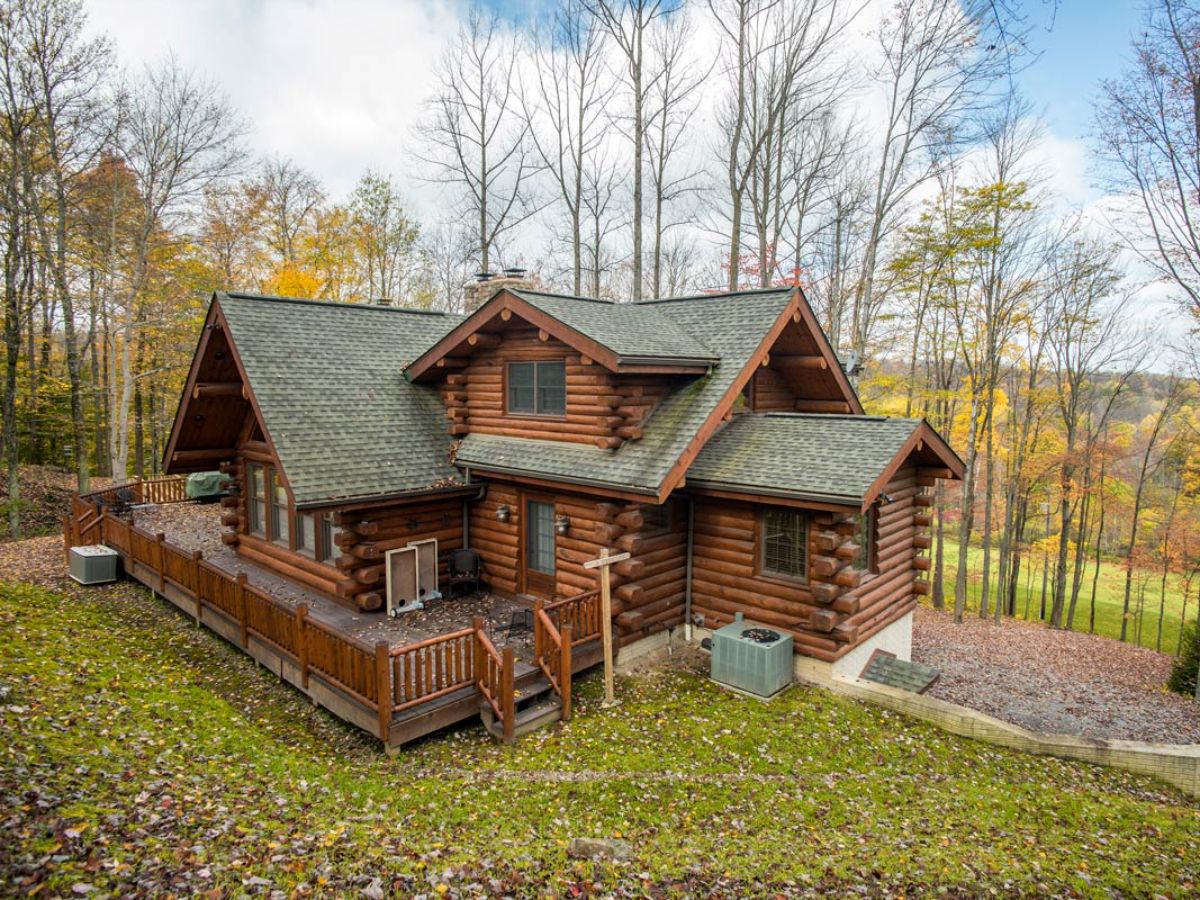 dark brown stain log cabin with open porch and green roof