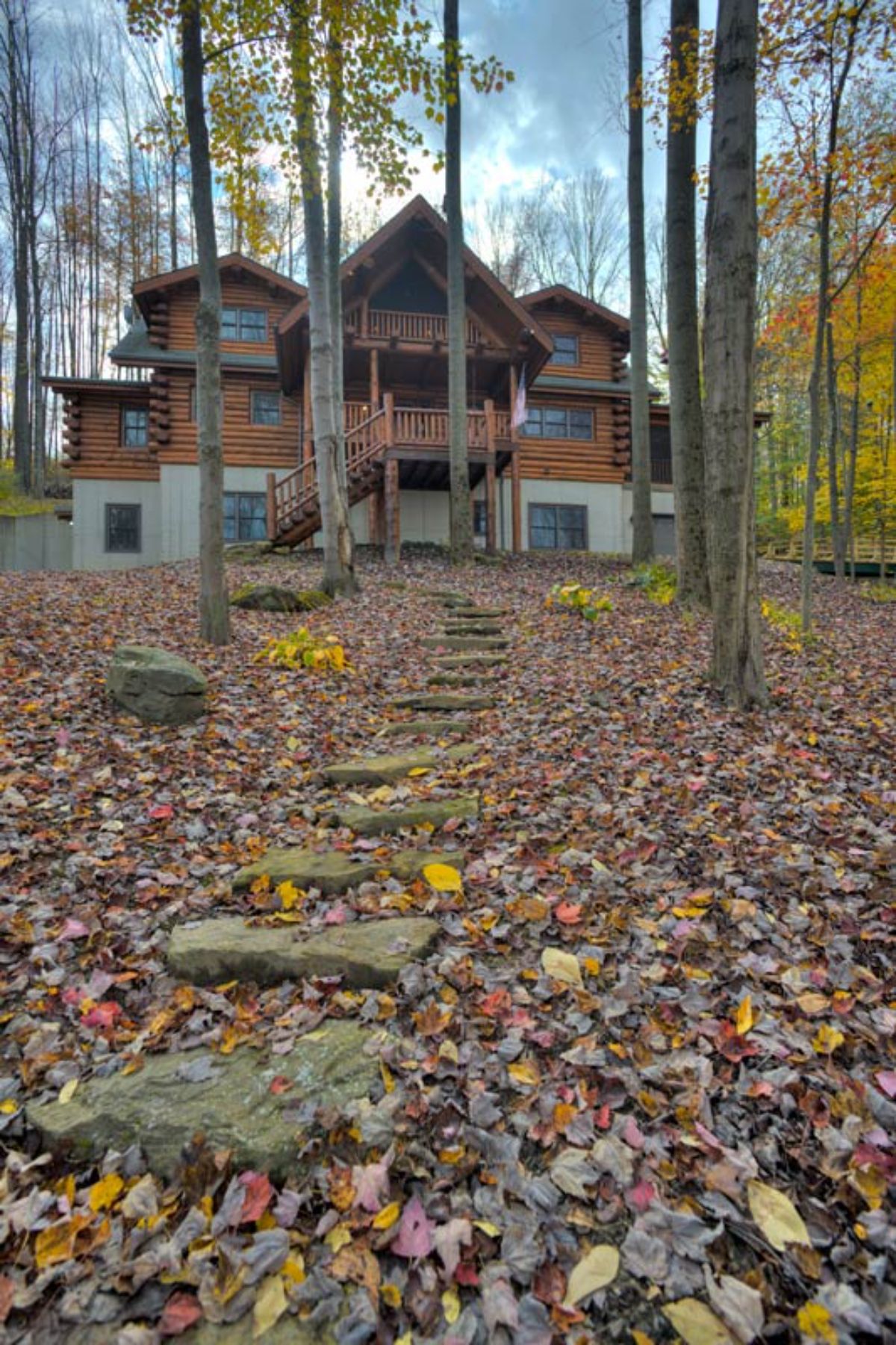 stone path up to back of log cabin with green roof and walkout basement