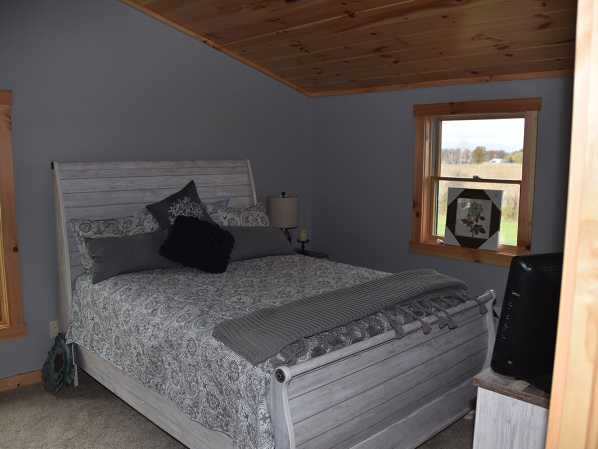 white bed against white bedframe in white bedroom of log cabin