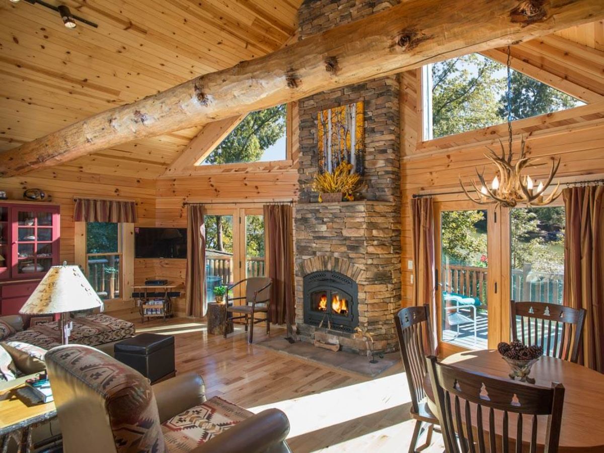 back wall of log cabin with fireplace between glass doors with trapezoid windows above