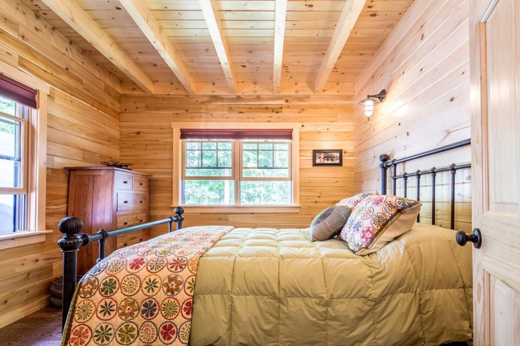 quilt on bed with wrought iron frame in log cabin bedroom