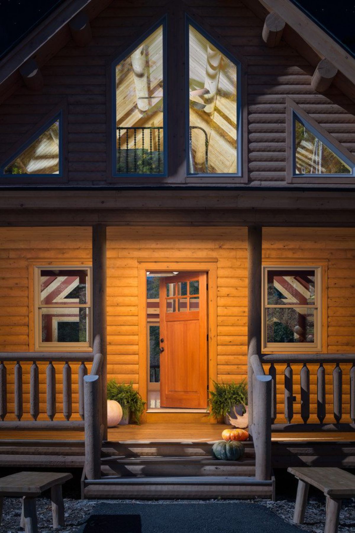 front door to log cabin with windows above and covered porch