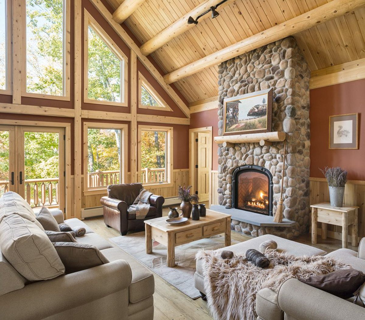 fireplace against wall of log cabin living room with wall of windows on left