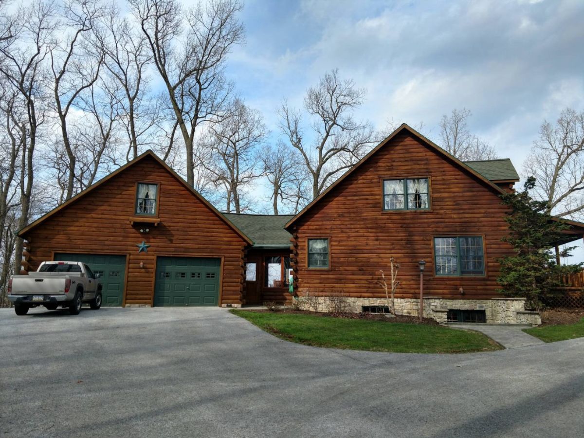 circle drive in front of log cabin with green garage doors