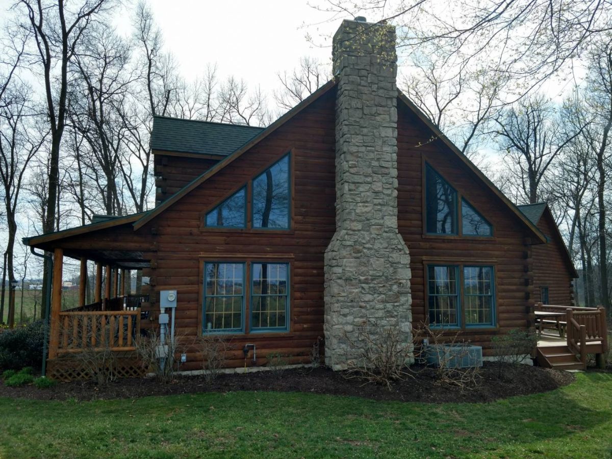 side of log cabin with stone chimney