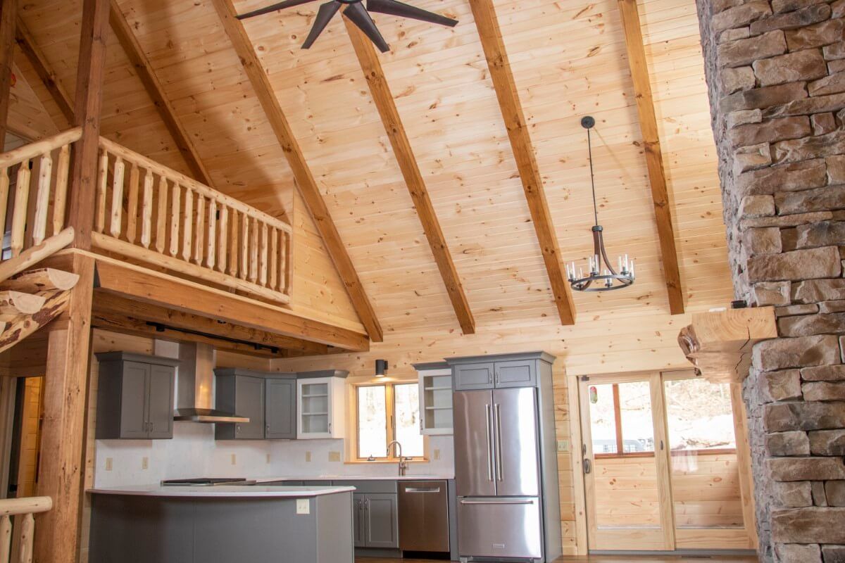 kitchen in corner of log cabin great room with high ceilings and loft above kitchen