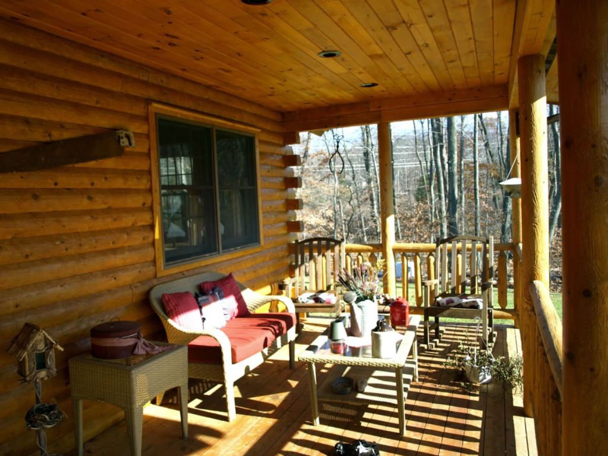 wicker furniture on log cabin porch with red cushions